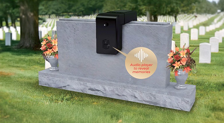 flashback-monument FlashBack audio memorial device mounted on a cemetery headstone, with flowers on each side and a label reading “Audio player to reveal memories.”